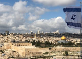 International delegation of ambassadors begins diplomatic visit to Israel A view of Jerusalem with the Israeli flag in the foreground. Credit: John Theodor/Shutterstock.