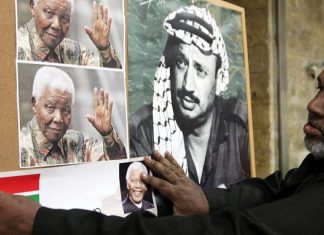 Israel slams South Africa parliament decision to downgrade ties A Palestinian man hangs a picture of former South African leader Nelson Mandela next to a poster of former Palestinian chief Yasser Arafat, at a memorial service for Mandela in Jerusalem's Old City on Dec. 8, 2013. Photo by Sliman Khader/FLASH90.