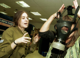 Record number of religious women enlist in IDF’s Shlav Bet A soldier teaches a woman how to wear and use a gasmask during the Second Intifada, Oct. 30, 2001. Credit: Flash90.